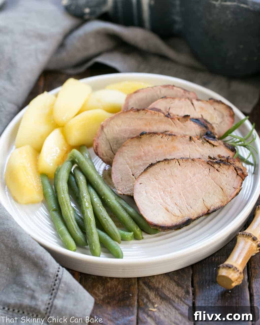 Maple Grilled Pork Tenderloin after being sliced and plated, ready for serving with sauteed apples and green beans.