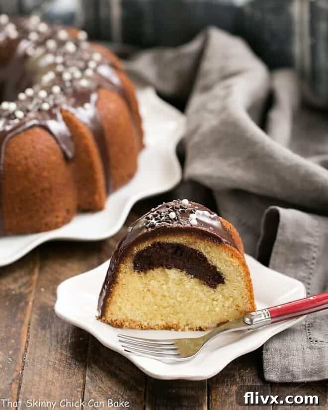 Slice of Tunnel of Fudge Cake on a square white plate with a red handled fork, showing the decadent fudge tunnel within.