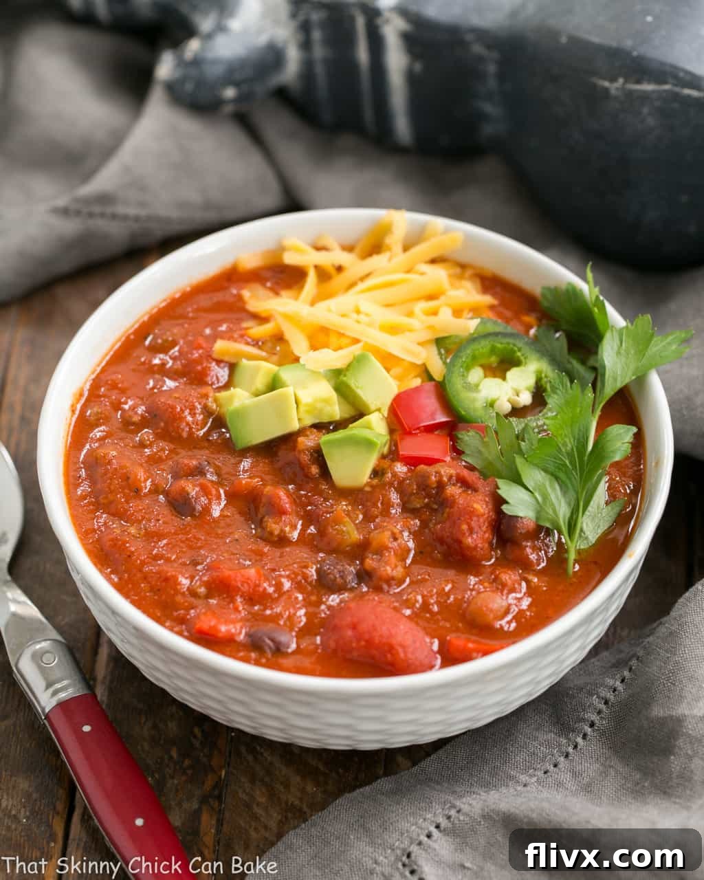 Easy Black Bean Chili in a white soup bowl, garnished with cheese and fresh herbs.