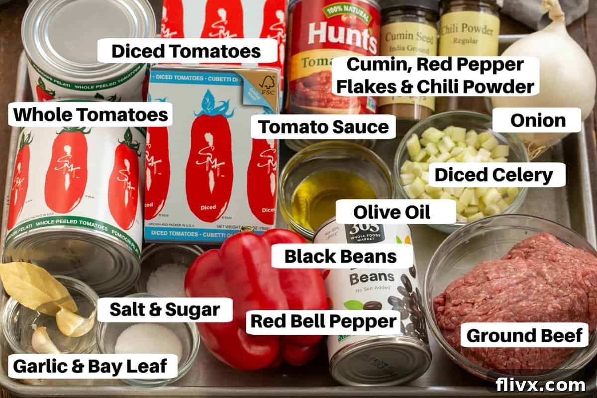 Black Bean Chili Ingredients with labels on a sheetpan, showcasing fresh vegetables, canned goods, and spices.