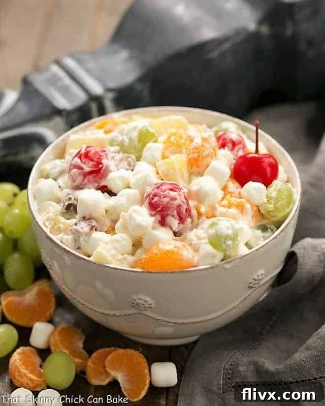 The Best Ambrosia Salad {No Cool Whip} in a beautiful white ceramic bowl, garnished with fresh fruit.
