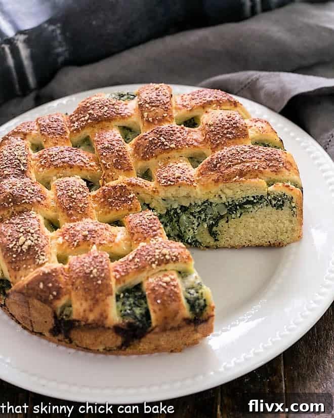 Spinach Torta Rustica with a wedge removed, showcasing the tender, buttery yeast bread and rich spinach ricotta filling, served on a white plate.