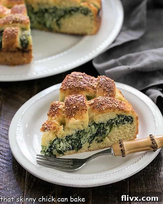 A delectable slice of Cheesy Stuffed Bread, featuring the rich spinach ricotta filling and tender yeast crust, presented on a white plate with a bamboo-handled fork.