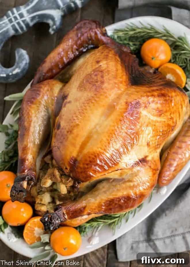 Honey Brined Turkey on a white platter garnished with herbs and oranges, close up.