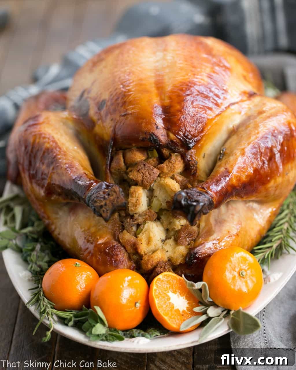 Honey Brined Turkey Recipe view of stuffing end with herbs and oranges. Roasted turkey on a white platter.