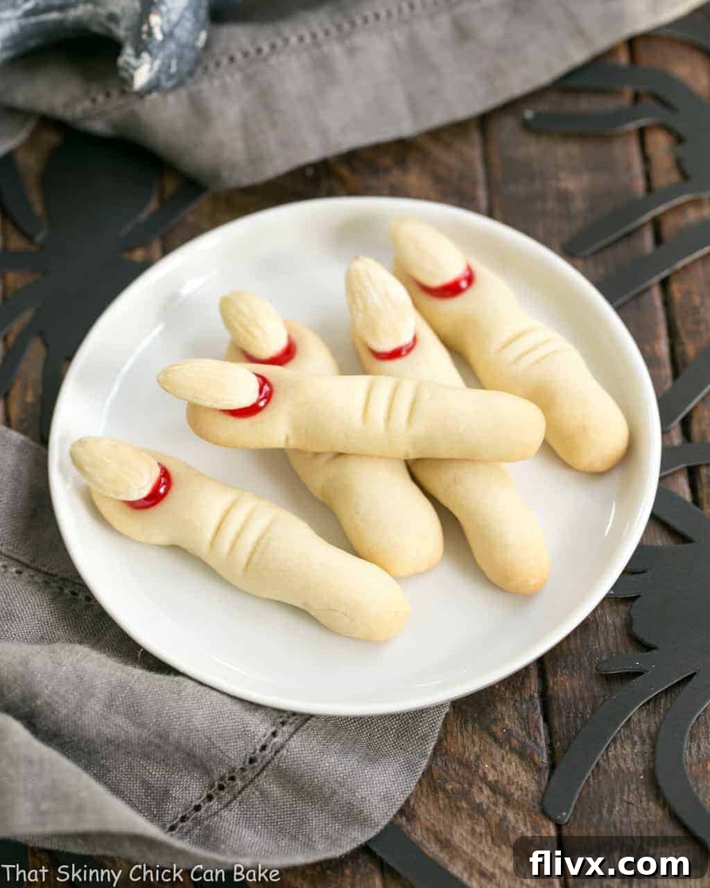 Witches Fingers Cookies artistically arranged on a round white ceramic plate, showcasing their gnarled texture and almond nails.