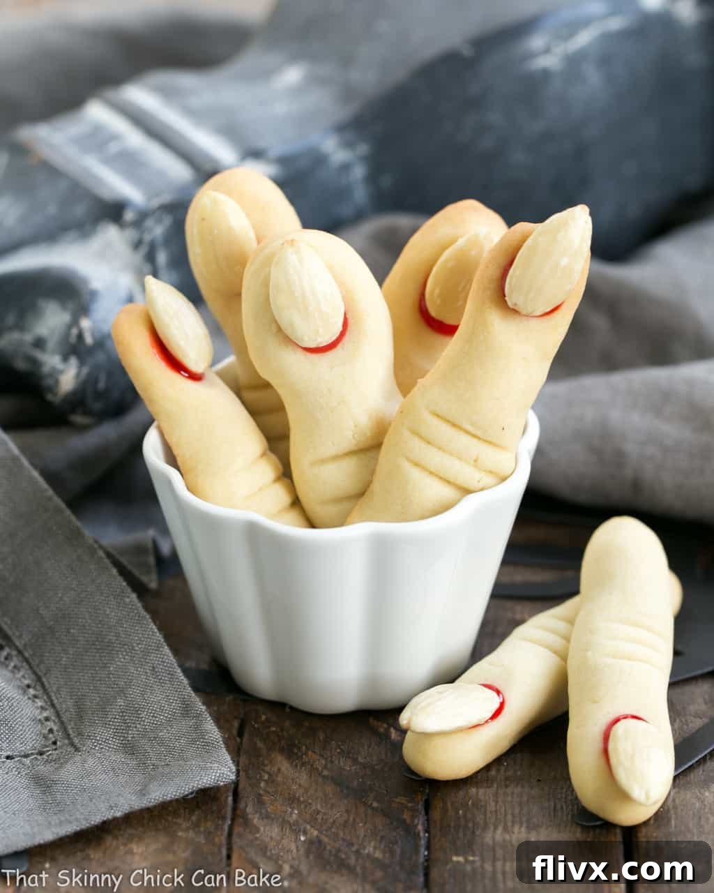Witches Fingers Cookies standing upright in a white ramekin, highlighting the detailed knuckles and 'bloody' nail beds.