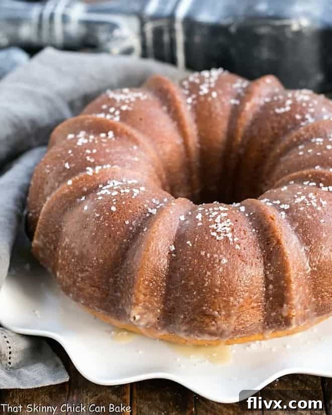 A full Kentucky Butter Bundt Cake presented on a beautiful wavy-edge white cake plate, ready to be sliced.