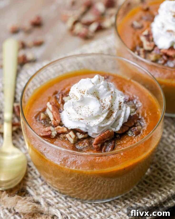 A bowl of rich, creamy Pumpkin Custard topped with a generous swirl of whipped cream and a sprinkle of cinnamon.