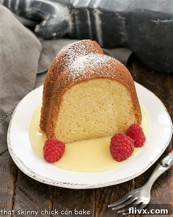 A delicious slice of white chocolate pound cake artfully arranged on a dessert plate, accompanied by fresh raspberries and a decadent white chocolate sauce.