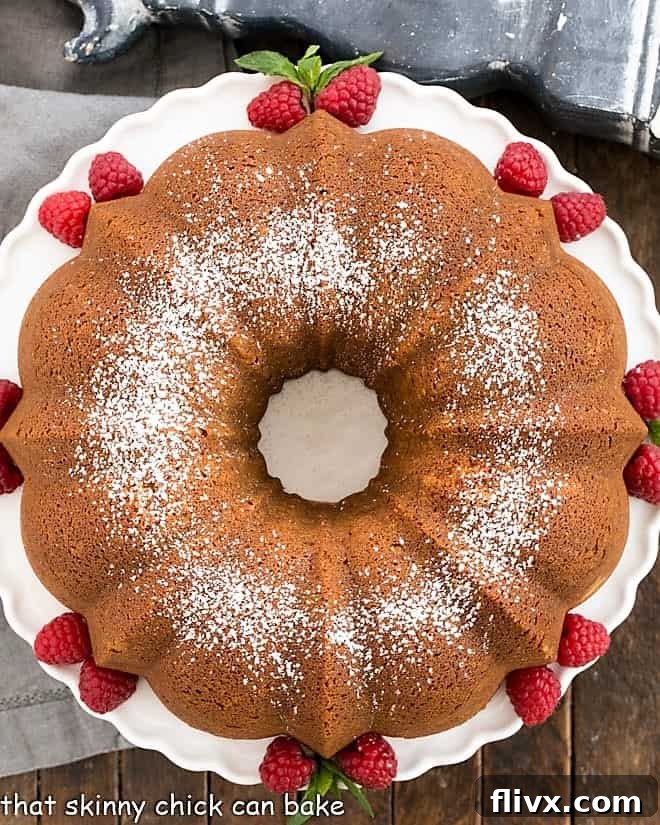 An inviting overhead shot of the whole white chocolate pound cake, elegantly displayed on a pristine white cake stand, ready to be served.