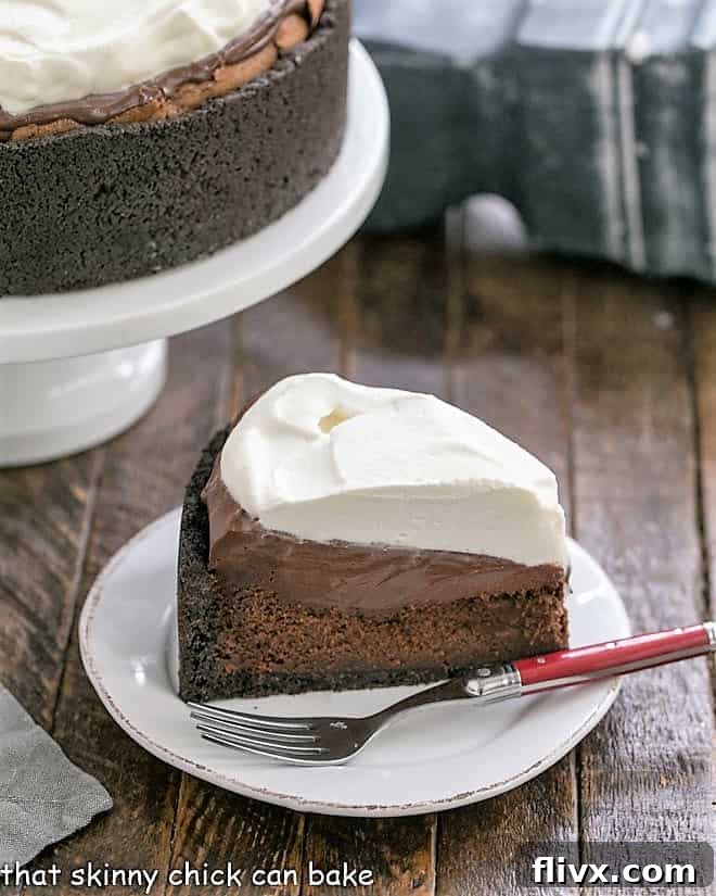 A close-up shot of a single, perfectly cut slice of Mississippi Mud Pie, artfully presented in front of the full pie on a cake stand. This image highlights the intricate layers, rich textures, and inviting appearance of this ultimate chocolate dessert, ready to be savored.