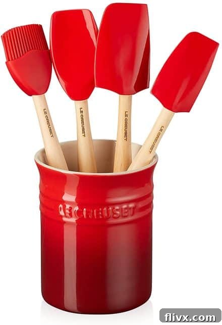 Red crock filled with Le Creuset spatulas, adding a pop of color to the kitchen.