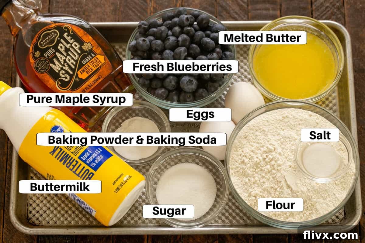 Pancake ingredients including eggs, flour, buttermilk, sugar, salt, baking powder, baking soda, and melted butter, neatly arranged on a metal sheet pan with labels.