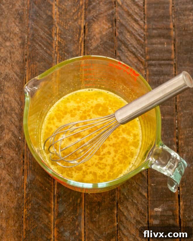 Whisking eggs in a bowl before adding other ingredients.