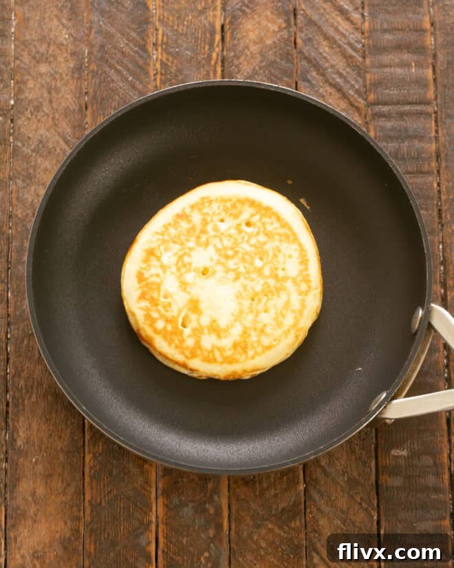Cooking pancakes on a lightly greased skillet with bubbles forming.