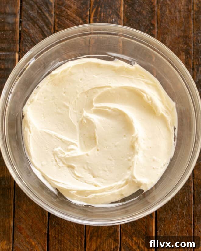 Overhead view of sour cream and cream cheese mixture being beaten in a bowl.