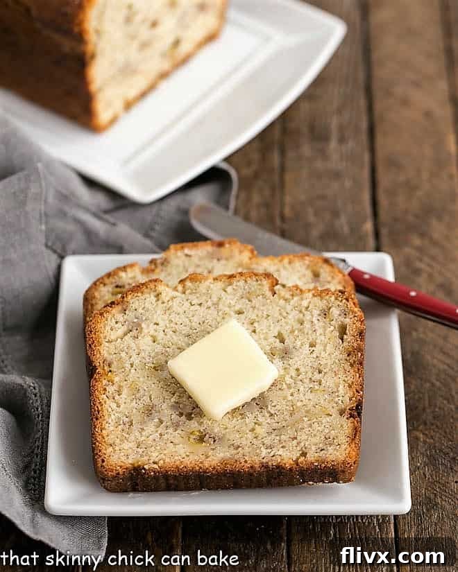Two perfectly sliced pieces of Buttermilk Banana Bread, served on a square white plate, adorned with a melting pat of butter, emphasizing its moistness and inviting texture.
