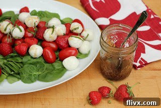 A different angle of the strawberry Caprese salad on a white oval plate, showing the generous portions of ingredients and the fresh basil leaves.