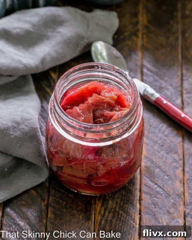 Rhubarb compote in a glass canning jar with a red handle spoon, showcasing its rich texture and color.