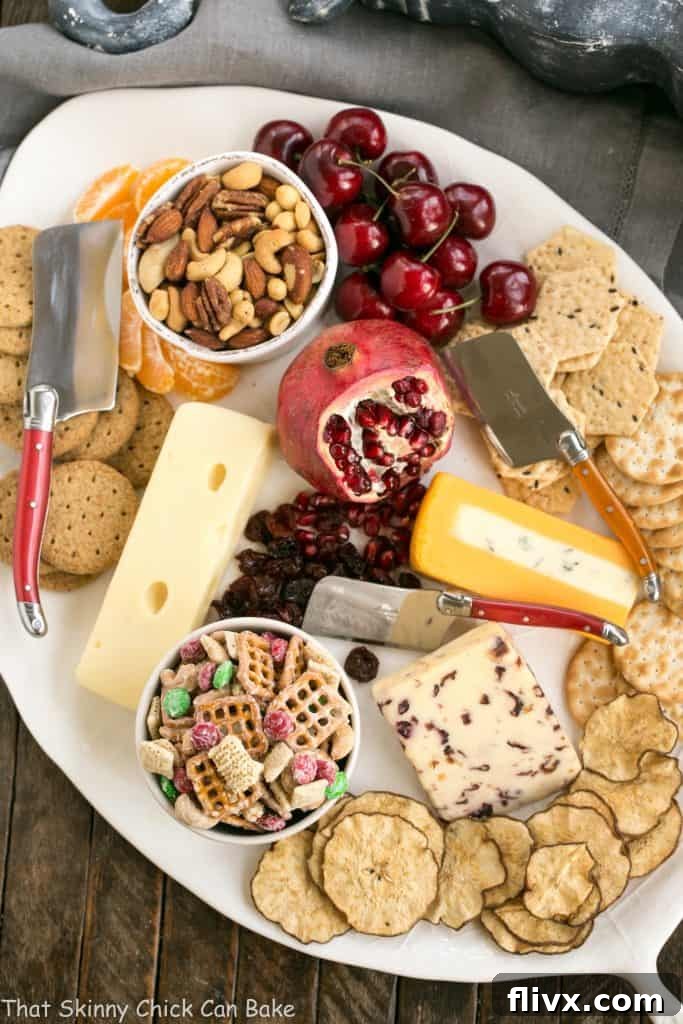 An elaborate and beautifully arranged holiday cheese platter, showcasing a variety of cheeses, fresh fruits, crackers, and the White Chocolate Cashew Party Mix