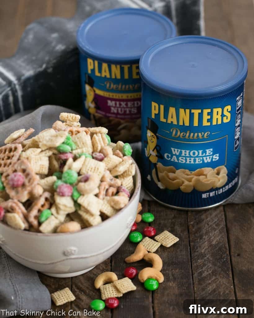 A large bowl of White Chocolate Cashew Party Mix prominently displayed next to several cans of Planter's roasted nuts, emphasizing the premium ingredients used in the recipe