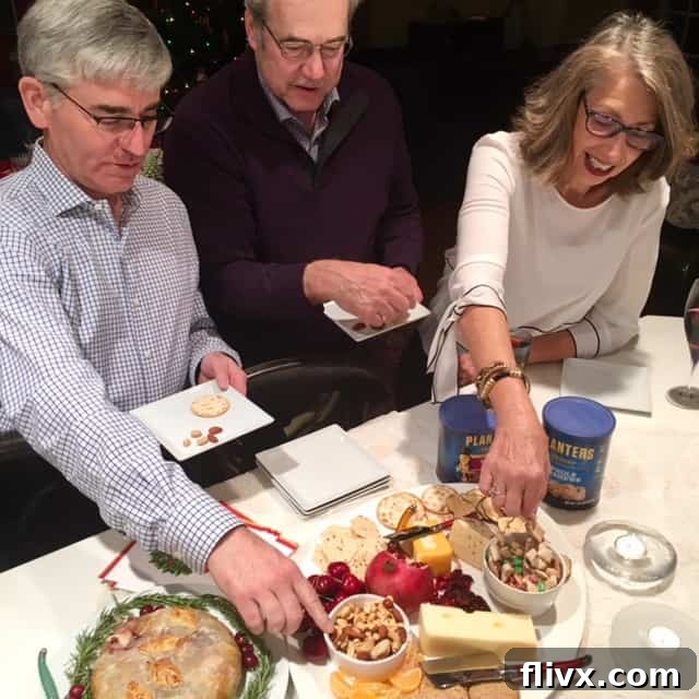 A group of smiling party guests enjoying a variety of party foods, including a bowl of the irresistible White Chocolate Cashew Party Mix and delicious dips