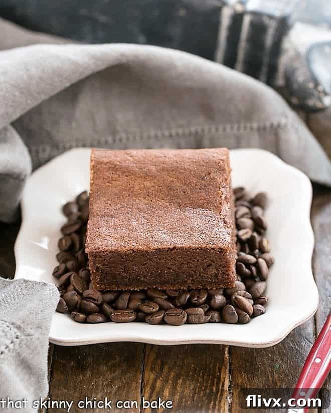 Close-up of a plate of Kahlua Brownies nestled on a bed of aromatic coffee beans, highlighting their fudgy texture.