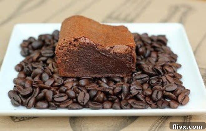 Close-up of a Kahlua Brownie on a white plate, garnished with coffee beans.