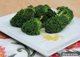 A collection of fresh ingredients for the recipe: green broccoli heads, bright yellow lemons, and whole garlic cloves.