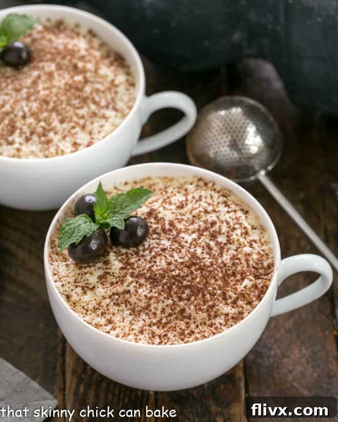 Two cups of chocolate tiramisu with a dusting wand full of cocoa powder, ready to be served and enjoyed.