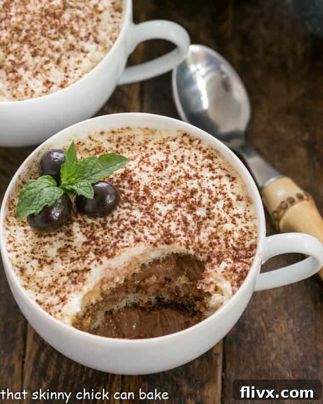 A cup of chocolate tiramisu with a spoonful removed, showing the layers of chocolate mousse and espresso-dipped ladyfingers.