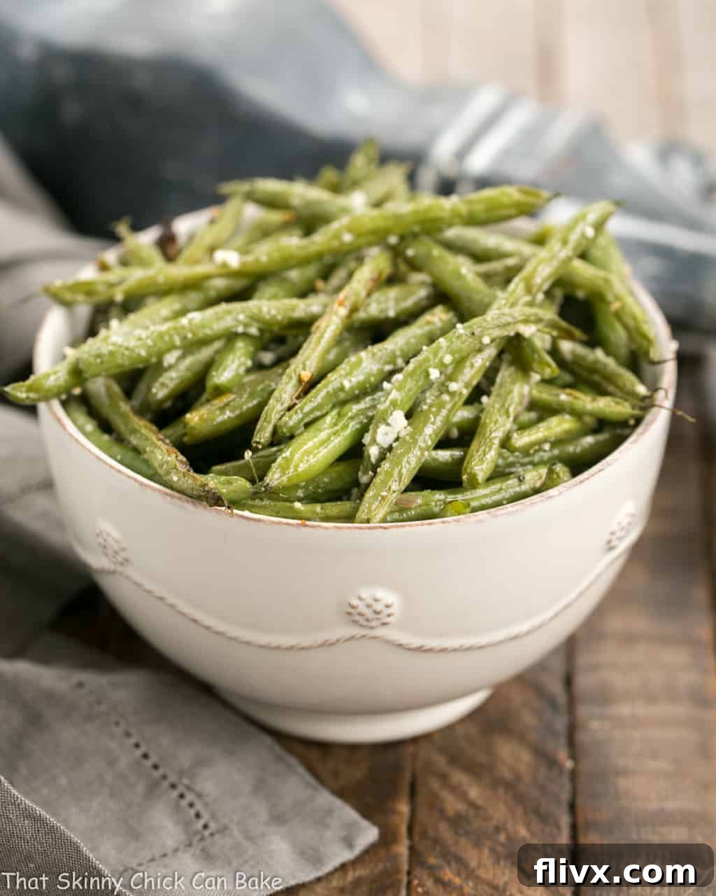 Garlic Parmesan Roasted Green Beans served in a white bowl, garnished with fresh herbs.