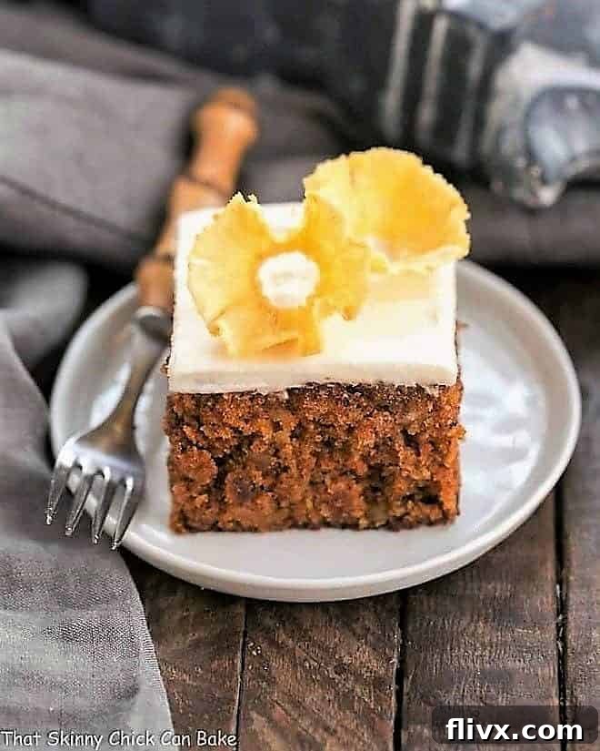A perfectly sliced piece of moist Old Fashioned Carrot Cake on a white plate, showcasing its rich texture and delectable cream cheese frosting.
