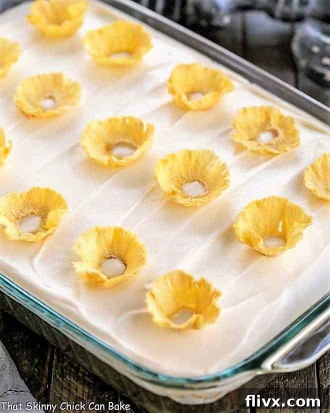 A beautifully frosted one-layer Old Fashioned Carrot Cake topped with delicate, golden pineapple flowers, ready for serving.