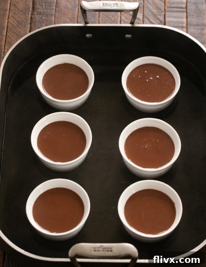 Pour strained chocolate custard into ramekins and add hot water to the baking dish to create a bain-marie.