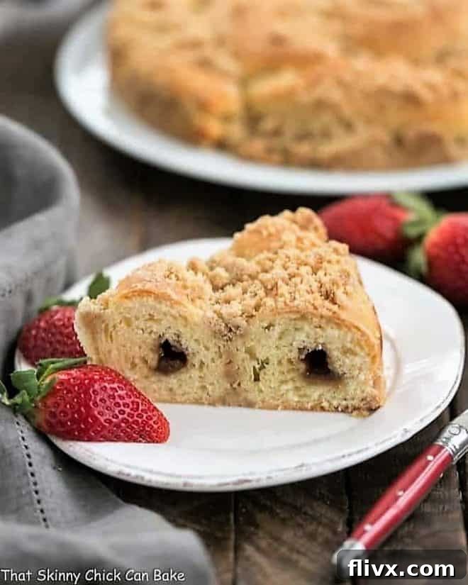 Slice of Streusel Coffee Cake Recipe on a white plate with strawberries, highlighting its tender crumb and cinnamon swirl.