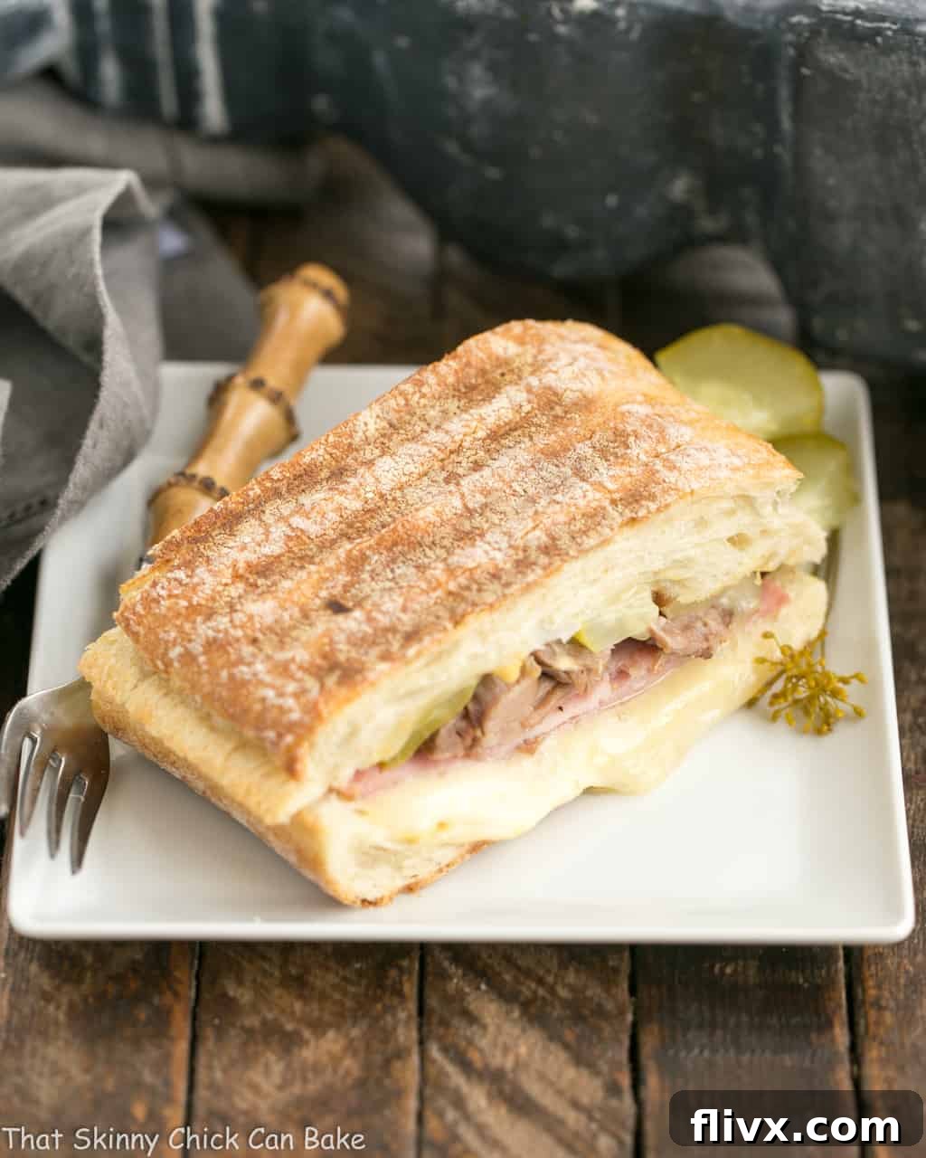 Ciabatta Cubano Sandwich on a square white plate, cut in half to reveal its enticing layers.