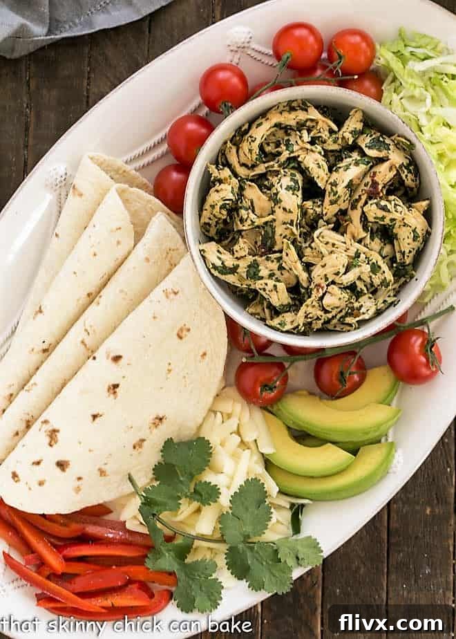 A vibrant serving platter laden with shredded chicken, warm tortillas, and an assortment of fresh toppings, garnished with cilantro.
