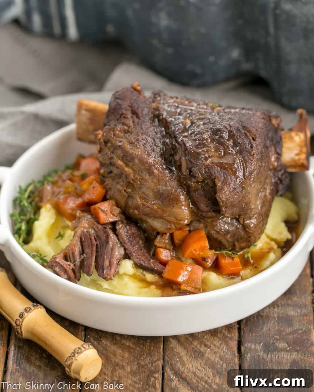 Instant Pot Beef Short Ribs on a round white plate over mashed potatoes and carrots.