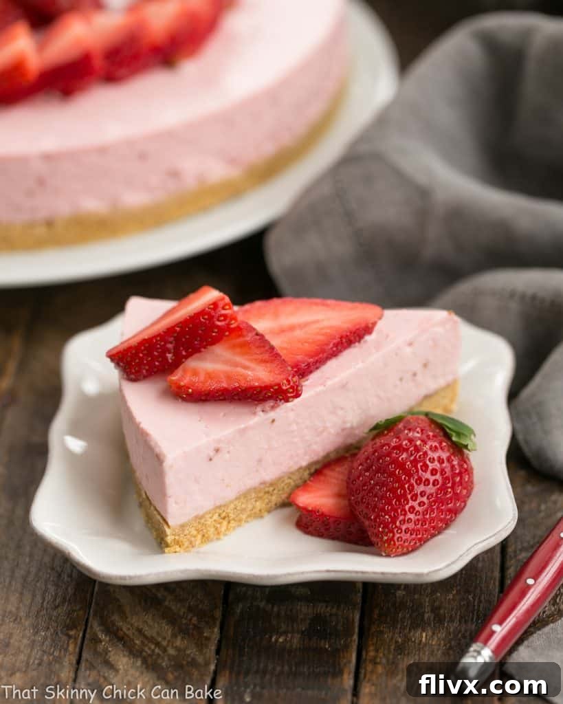 A perfectly sliced No-Bake Strawberry Cheesecake on a pristine white dessert plate, showcasing its creamy pink filling and crumbly graham cracker crust.