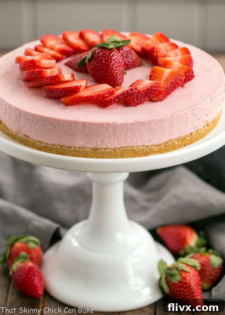 A stunning No-Bake Strawberry Cheesecake presented on a elegant white ceramic cake stand, ready to be served and enjoyed.