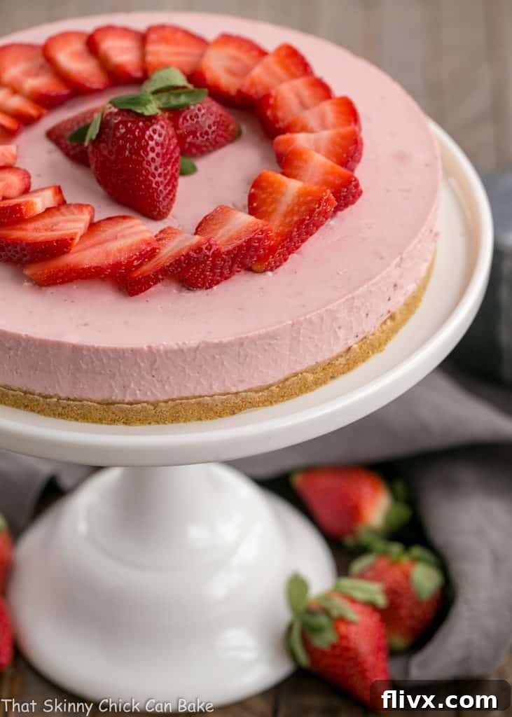 Overhead view of the smooth, perfectly set top of a No-Bake Strawberry Cheesecake on a cake stand, elegantly garnished with fresh strawberry slices.