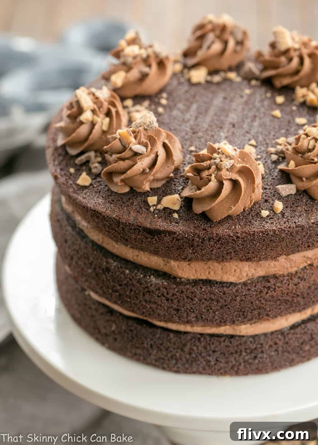 Triple Layer Chocolate Toffee Cake on a white cake stand, showcasing its three magnificent layers.