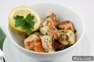 Close-up of freshly cooked chicken with vibrant green parsley and golden garlic bits in a skillet.