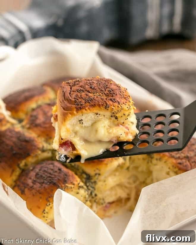 Corned Beef Sliders in a white casserole dish with a single slider on a black spatula, ready to be served.