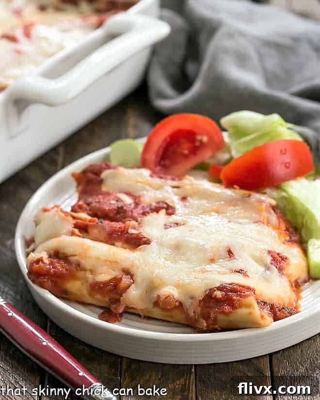 Cheese Manicotti on a white plate with a lettuce salad.