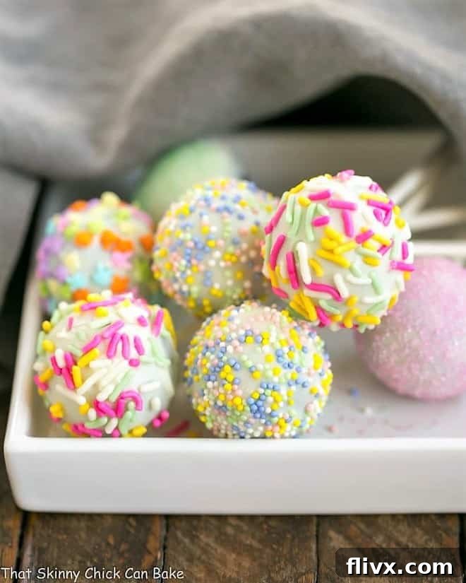 Two Easter Cake Pops, decorated with pastel sprinkles, resting on a small square white plate.