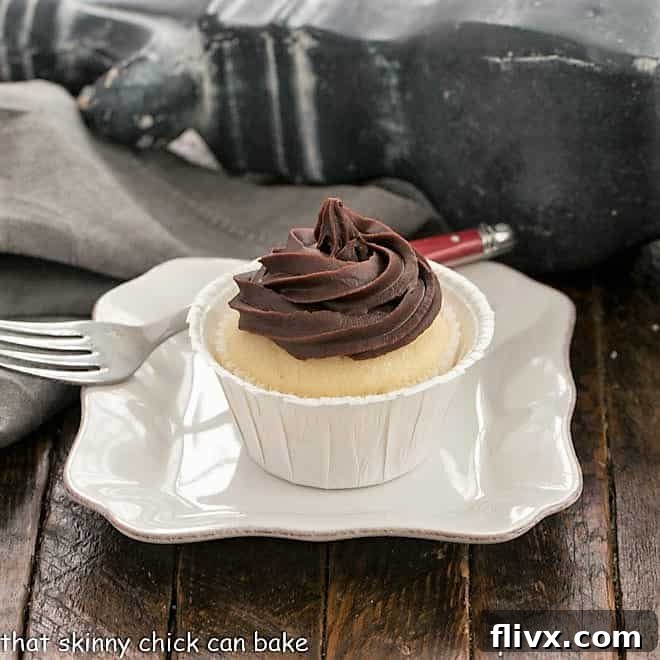 A boston Cream Pie Cupcake on white square plate with a red handled fork