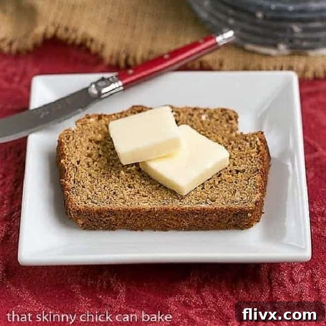 A perfectly baked slice of Easy Irish Brown Bread topped with a generous pat of melting butter, served on a square white plate, ready to be enjoyed.